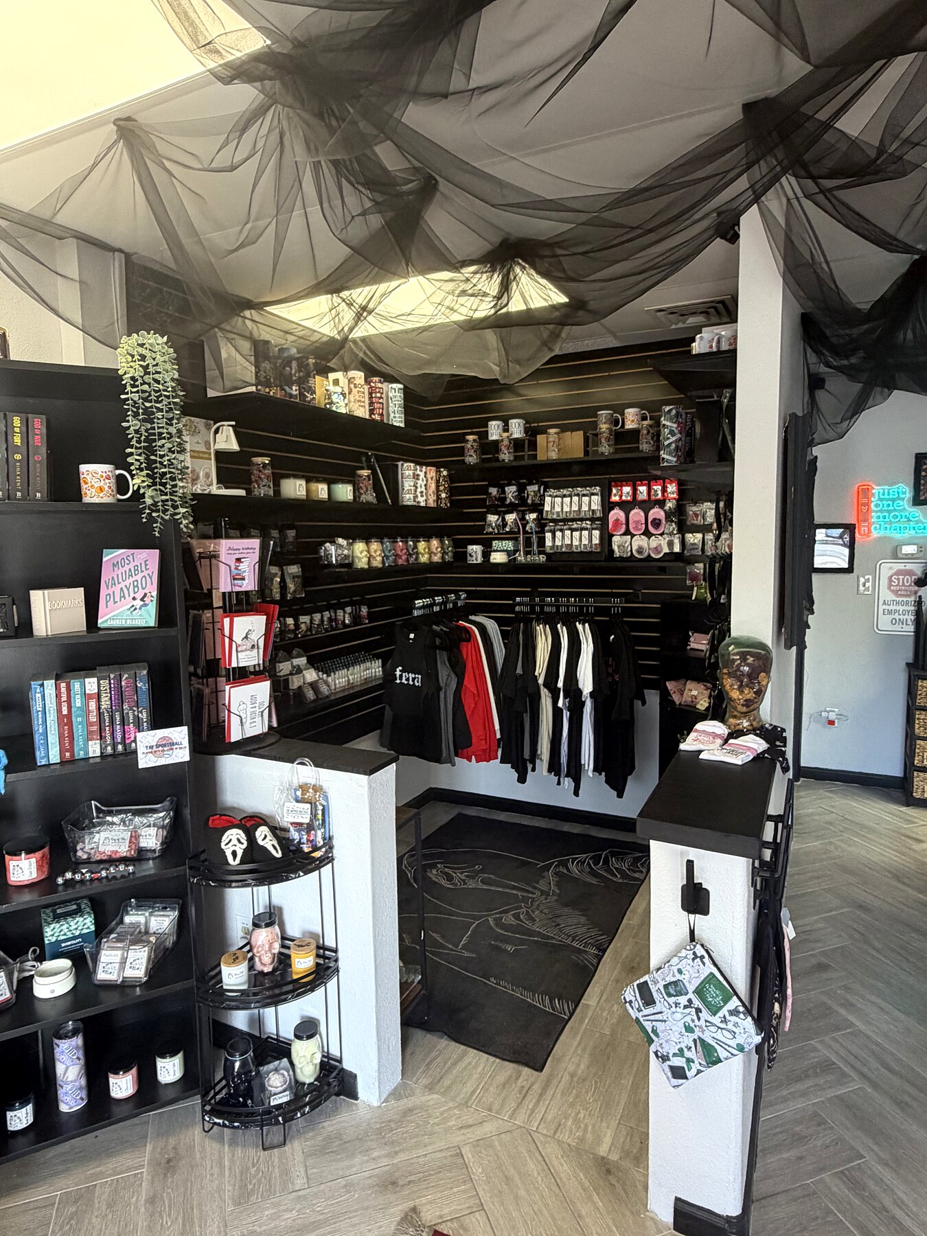 Inside The Damned Boutique — black tulle ceiling, romance shelves, candle cart and apparel rack